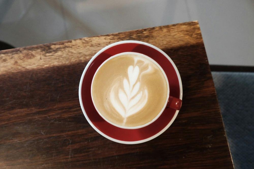 Latte con arte en la espuma en taza roja