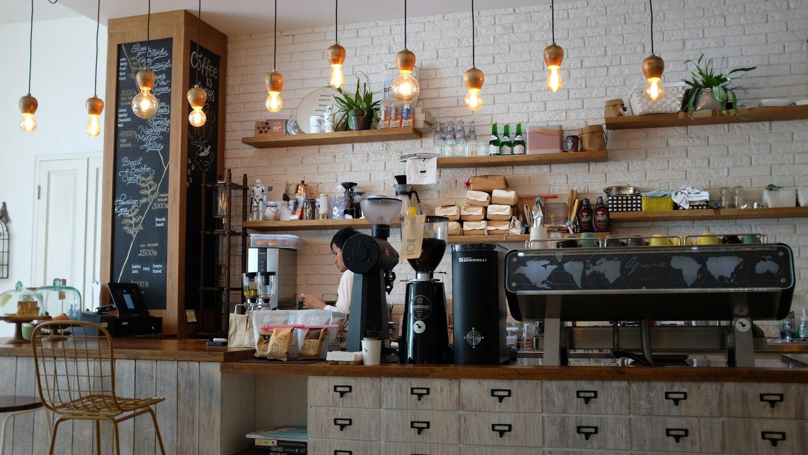 La barra de la cafetería con focos cálidos y repisas de madera